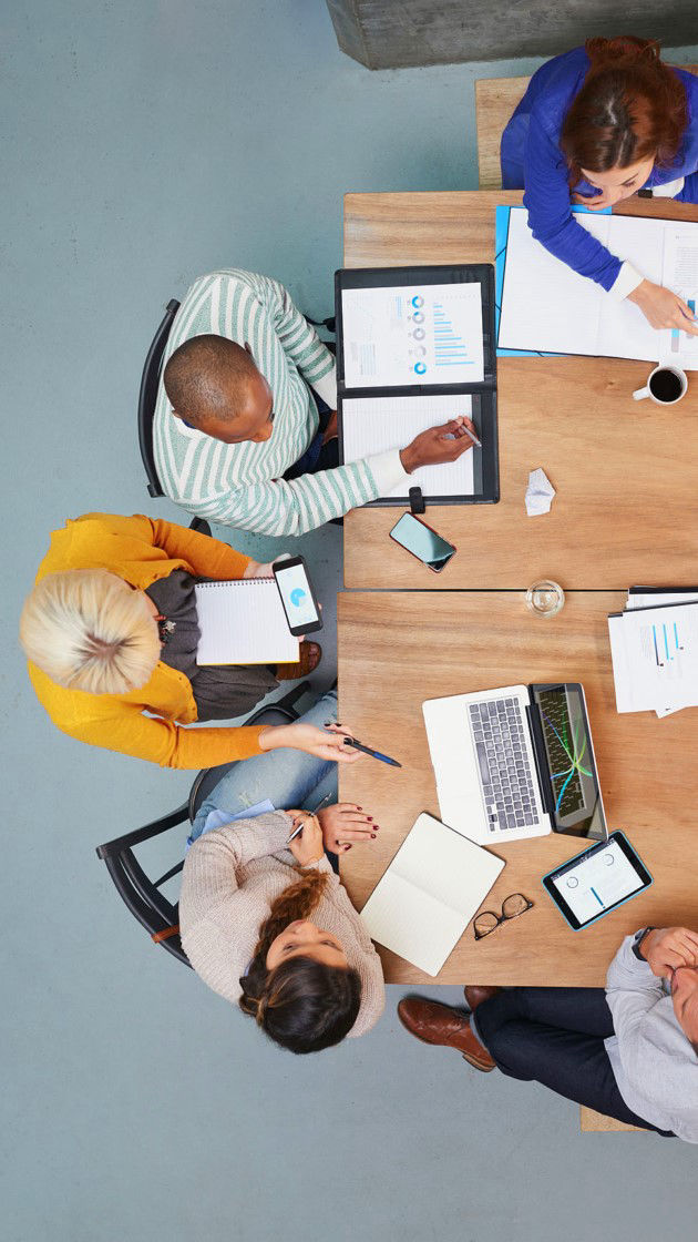 Professionally dressed people sitting at a table with a view from the top of the table looking down on their heads.